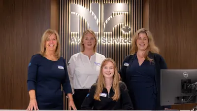 Image of the At Your Service counter and four city staff standing behind the counter smiling.