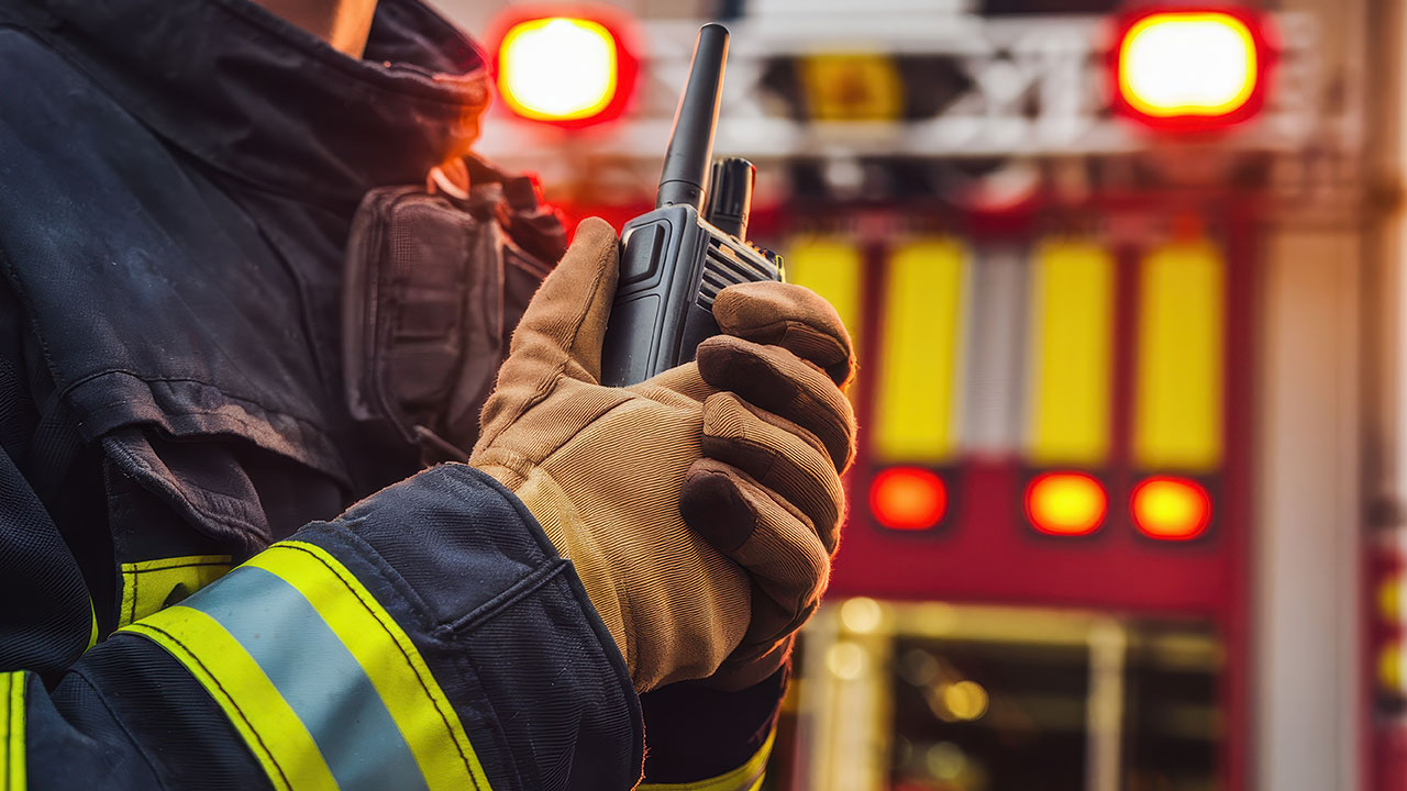 Firefighter holding radio in front of fire truck