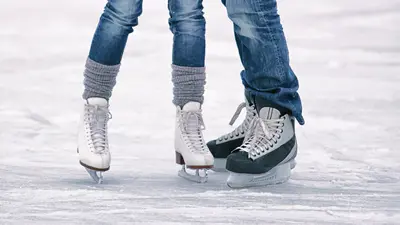 Close up of a couples legs, wearing ice skates at an ice rink