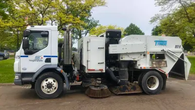 Side view of a parked City of Niagara Falls street sweeper.