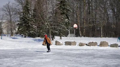 Outdoor ice rink at John Allan Park in Niagara Falls. A person is skating on a winter day.