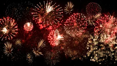 Colourful red and white fireworks in the night sky.
